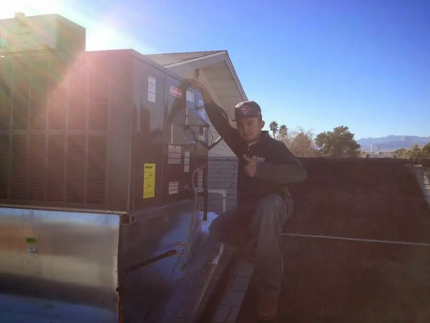 HVAC technician performing HVAC Inspection on a rooftop unit in Justice